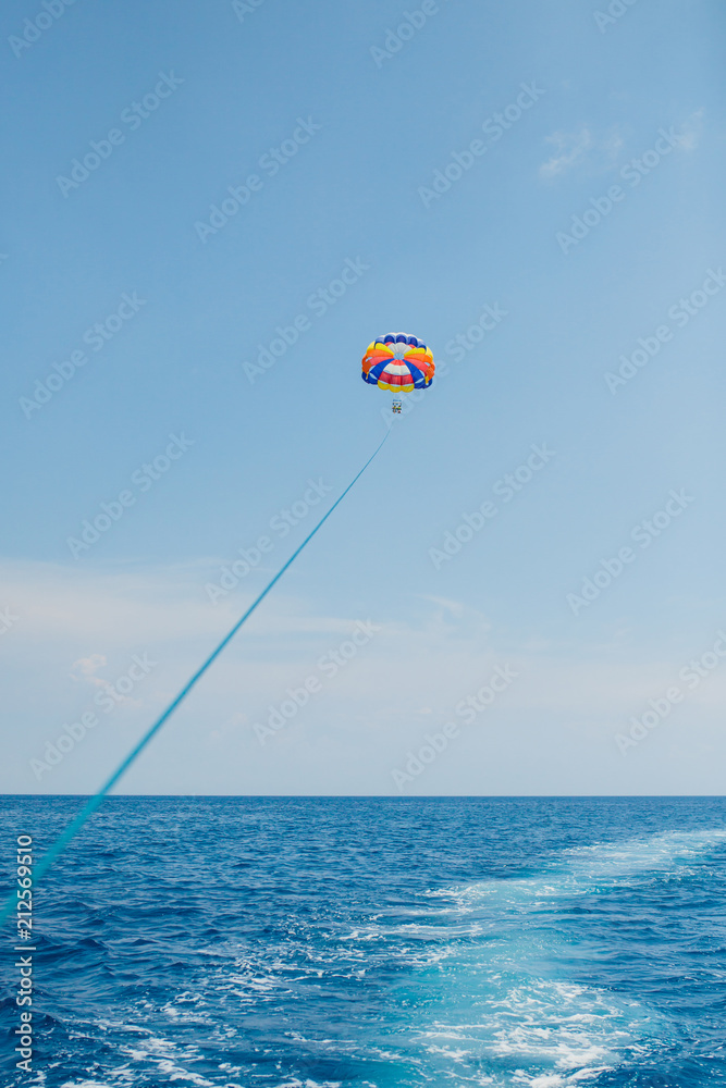 People flying on a colorful parachute towed by a motor boat