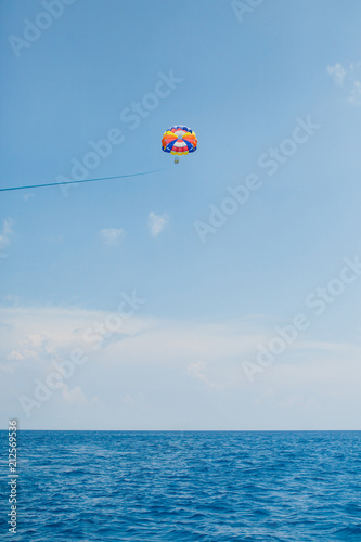 People flying on a colorful parachute towed by a motor boat