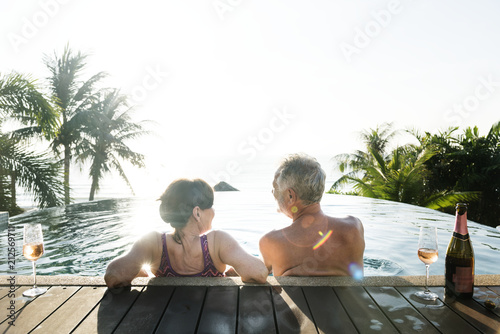 Senior couple drinking prosecco in a swimming pool