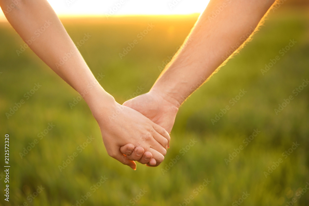 Young lovely couple holding hands in green field, closeup Young lovely couple holding hands in green field, closeup