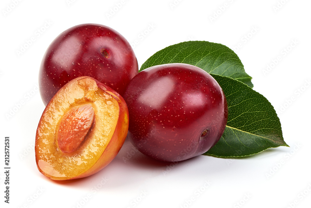 Ripe sweet red plums with leaves and a half of red plum fruit with core, isolated on white background. Close-up.