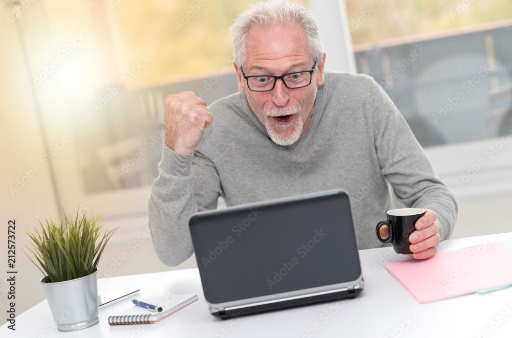 Happy mature man having a good surprise on laptop, light effect Happy mature man having a good surprise on laptop, light effect