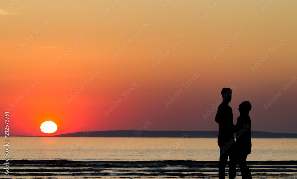 Silhouette of happy couple on the beach at sunset