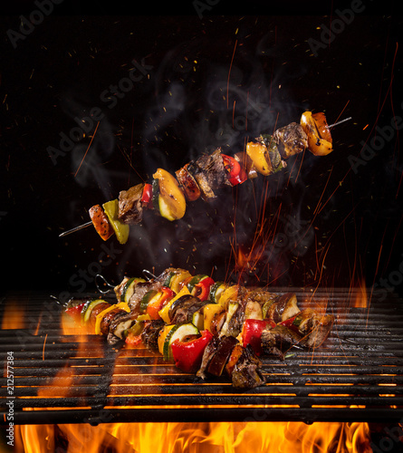 Tasty skewers on the grill with flames photo