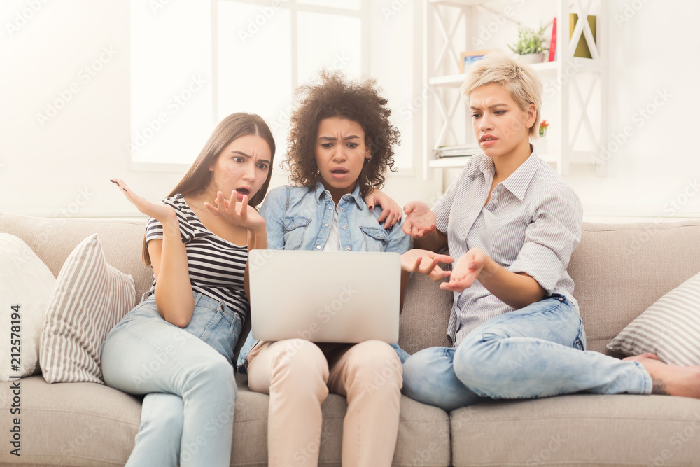 Three beautiful shocked women using laptop at home