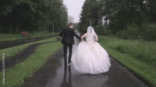 wedding in the rain. bride and groom are running in the rain