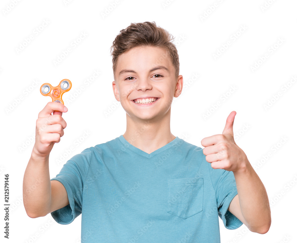 Young teen boy holding popular fidget spinner toy - close up portrait. Happy smiling child making thumb gesture and playing with Spinner, isolated on white background. Young teen boy holding popular fidget spinner toy - close up portrait. Happy smiling child making thumb gesture and playing with Spinner, isolated on white background.