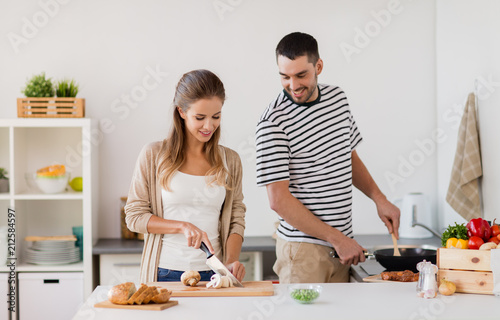 people and healthy eating concept - couple cooking food at home kitchen