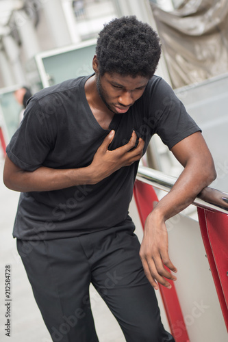sick african man with heart attack or chest pain; portrait of african man suffering from heart attack, chest pain, health care concept; young adult african man or black man model