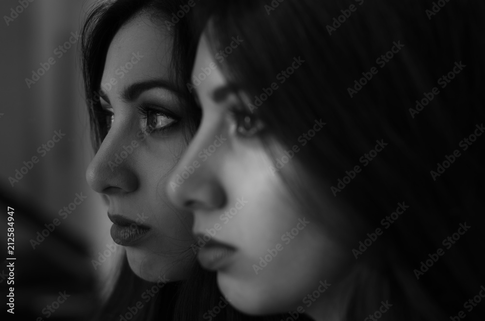 Young charming brunette girl looks at her reflection in the mirror Young charming brunette girl looks at her reflection in the mirror