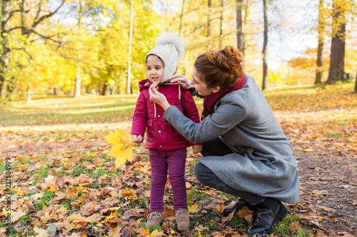 family, season and people concept - happy mother and little daughter with autumn leaves at park © Syda Productions