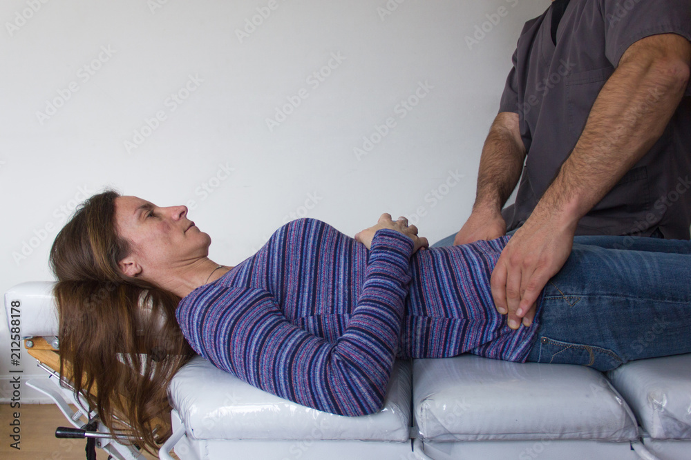 Fototapeta premium Female patient receives treatment from osteopath on hips area. Medical exam, injury, phisiotherapy concept