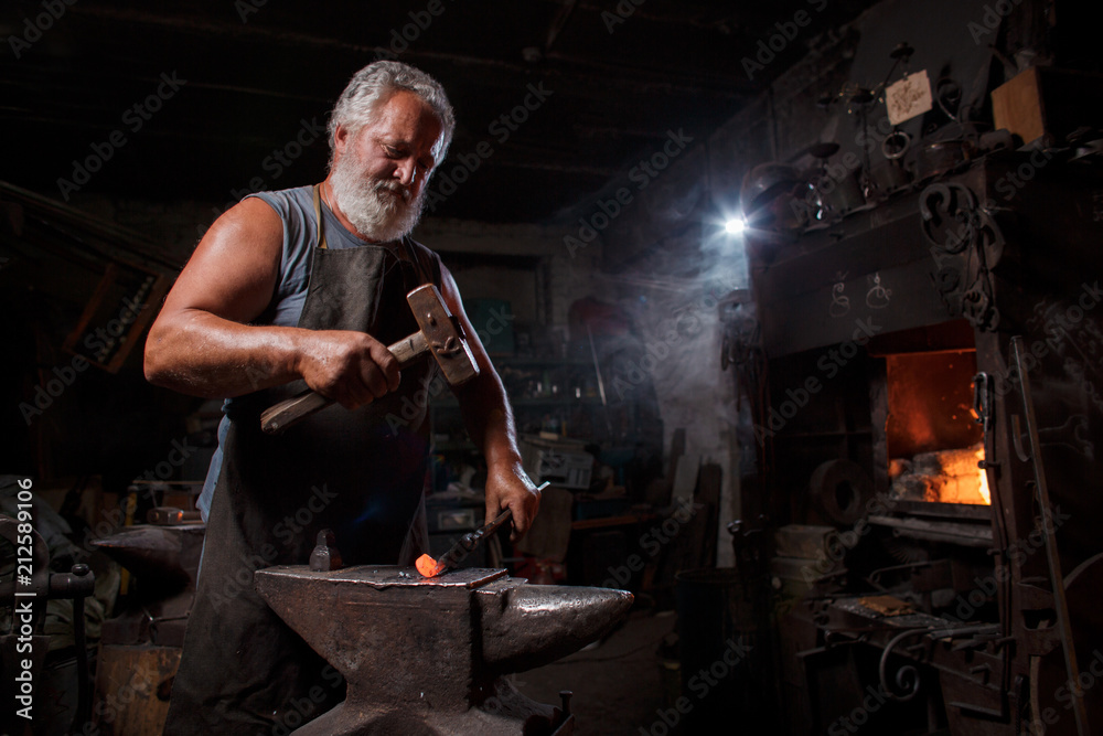Blacksmith with brush handles the molten metal Blacksmith with brush handles the molten metal