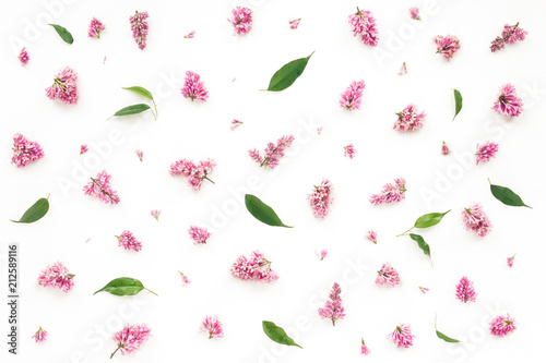 Lilac flowers and green leaves on white background. Flat lay, top view