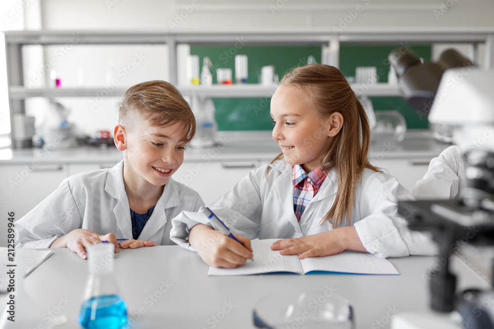 education, science and children concept - kids studying chemistry at school laboratory and writing to workbooks education, science and children concept - kids studying chemistry at school laboratory and writing to workbooks