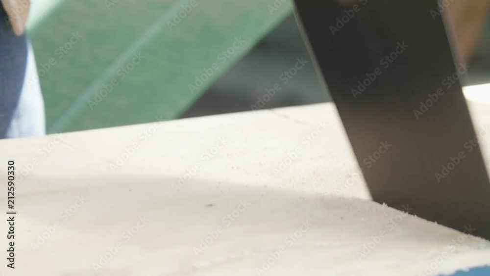 Cutting through a plank with a saw as seen from the side. Cutting through a plank with a saw as seen from the side.