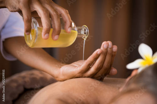 Therapist pouring massage oil at spa photo
