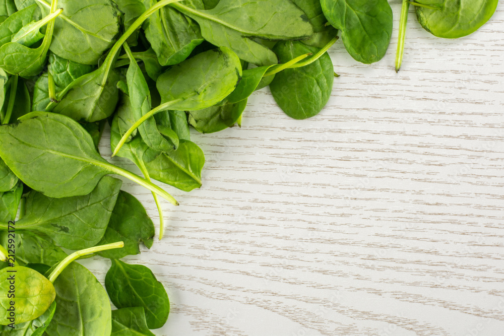 Fresh baby spinach leaves top view on grey wood background left upper corner. Fresh baby spinach leaves top view on grey wood background left upper corner.