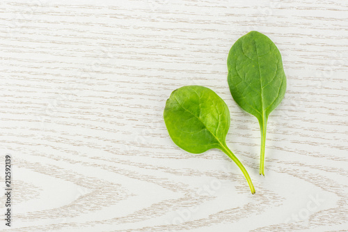 Fresh baby spinach top view on grey wood background two green single leaves. photo