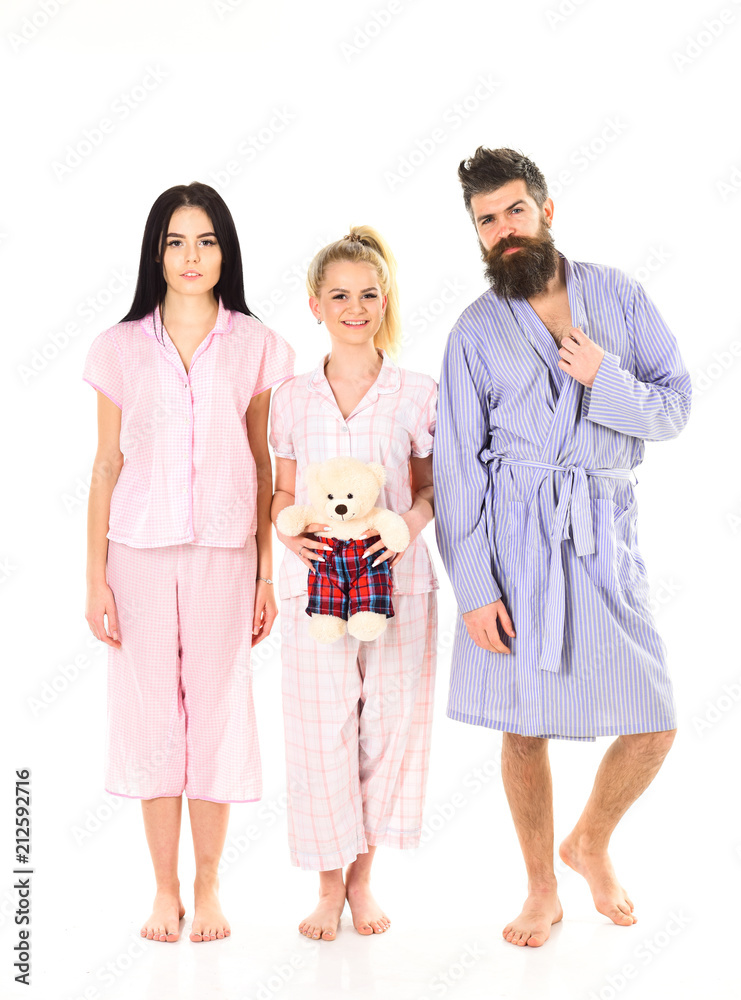 Girls with bearded macho in pajamas and robe in morning, isolated white background. Man with beard, cute blonde and brunette girls with toy bear just wake up in morning. Sleepy morning concept.
