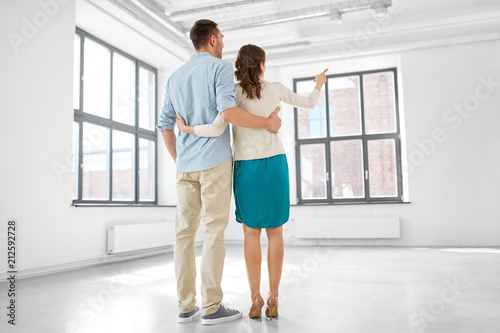 mortgage  people and real estate concept - happy couple hugging at new home from back