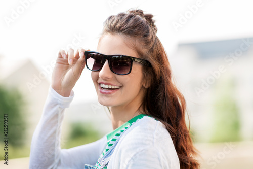 summer, eyewear and people concept - portrait of happy smiling young woman or teenage girl in sunglasses outdoors