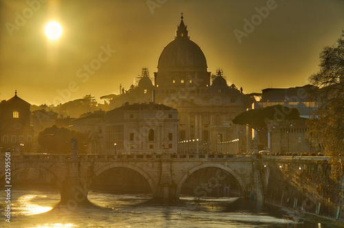 View of the Vatican over the River Tiber with the sun setting behind St. Peter’s Basilica.