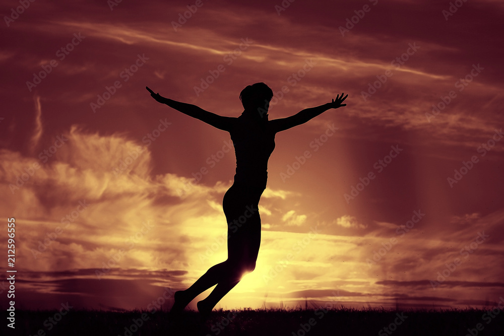 Silhouette of a girl against the sky jumping at sunset, concept of happiness