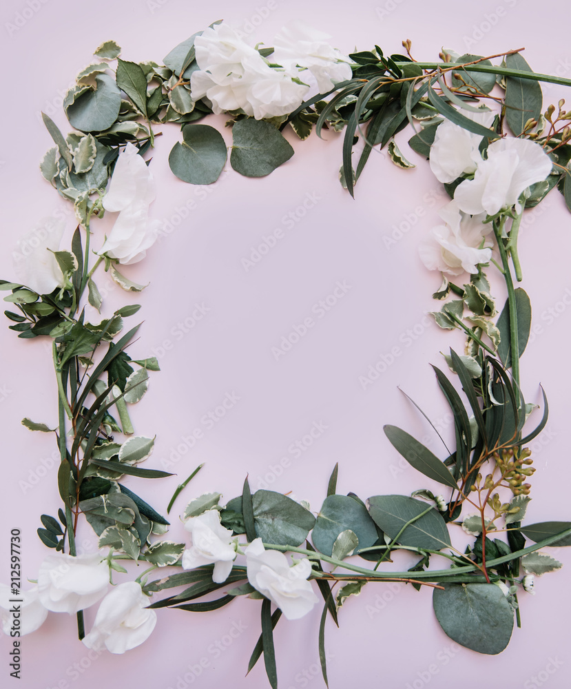 Naklejka premium Beautiful fresh floral frame out of eucalyptus leaves and branches and blossoming white lathyrus flowers on the tender pastel pink background