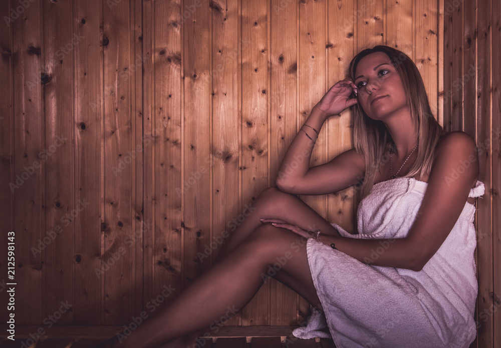 Young woman sitting on wooden bench in sauna