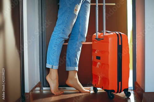 girl with a red suitcase leaves the room  the concept of tourism  departure  fees for the trip
