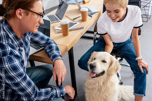 smiling young colleagues looking at dog in office photo