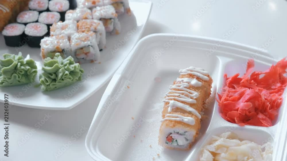 Woman puts rolls and wasabi from plastic packaging in a plate. Close-up hands. Woman puts rolls and wasabi from plastic packaging in a plate. Close-up hands.