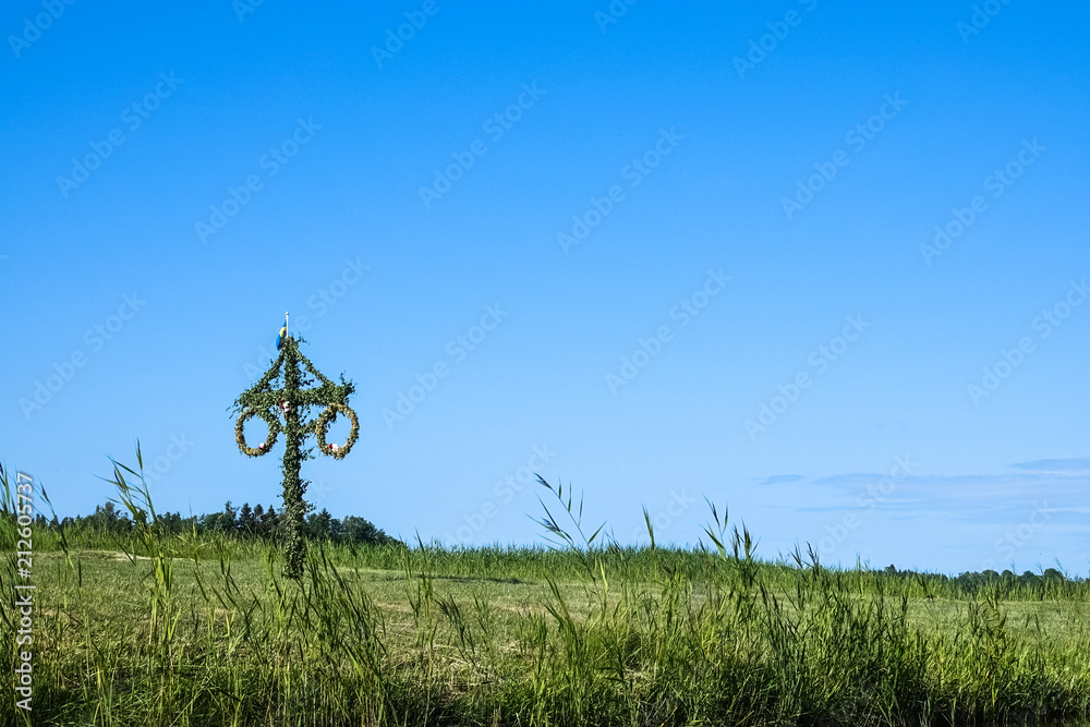 A Swedish maypole on a green summer meadow. - obrazy, fototapety, plakaty 