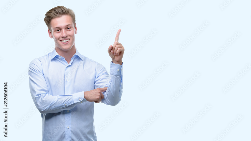 Young handsome blond man very happy pointing with hand and finger to the side Young handsome blond man very happy pointing with hand and finger to the side