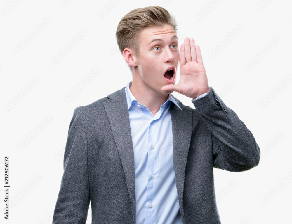 Young handsome blond business man shouting and screaming loud to side with hand on mouth. Communication concept. Young handsome blond business man shouting and screaming loud to side with hand on mouth. Communication concept.