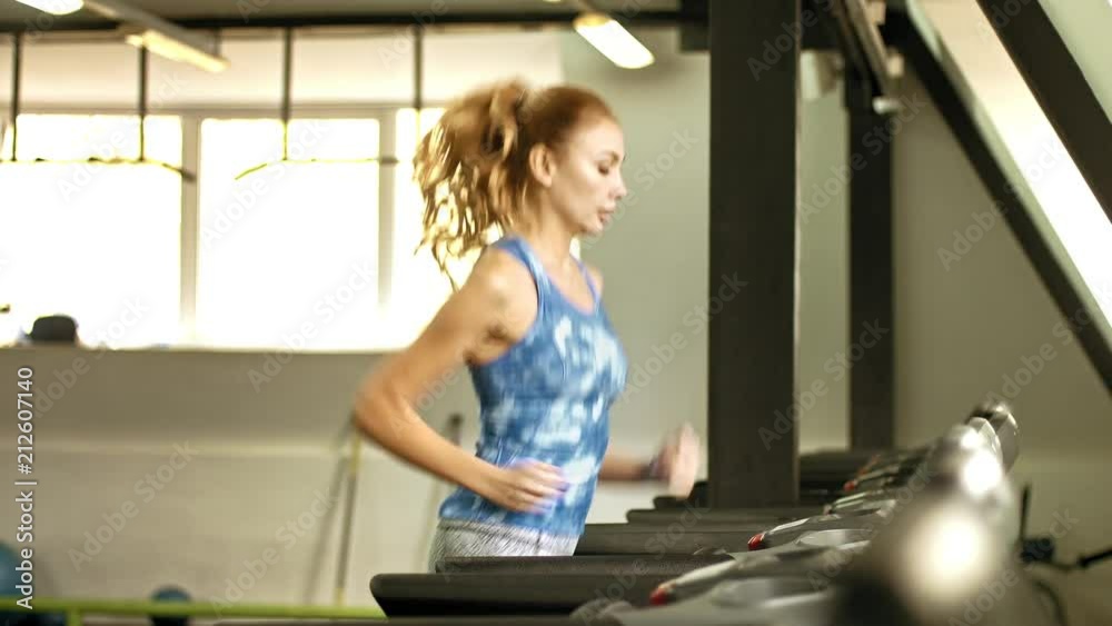 Beautiful young woman jogging on a treadmill at the gym Beautiful young woman jogging on a treadmill at the gym