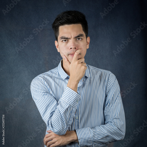 Portrait handsome young asian man wearing a white thinking and stress isolated on dark wall background.Asia man people. business concept.Copy space.