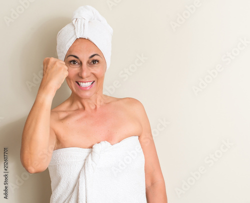 Beautiful middle age woman, wet hair wearing a towel annoyed and frustrated shouting with anger, crazy and yelling with raised hand, anger concept