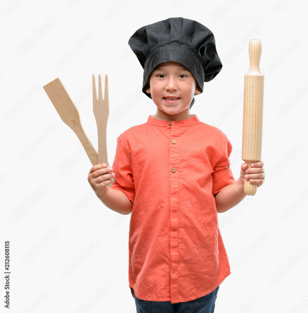 Fototapeta premium Dark haired little child wearing chef uniform with a happy face standing and smiling with a confident smile showing teeth