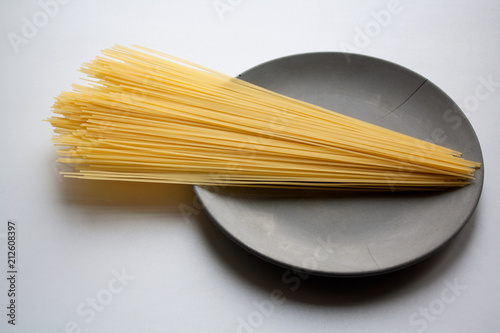 Stack of capellini pasta isolated on grey concrete plate photo