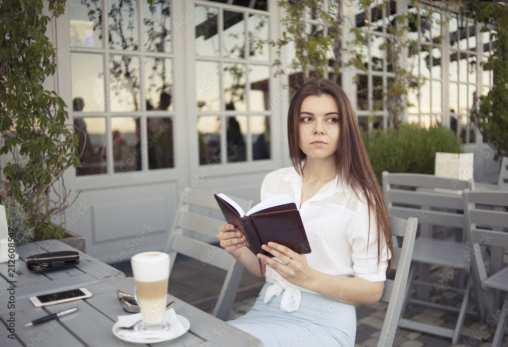 girl in a summer cafe with a book