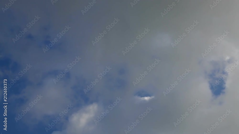 sky with fluffy clouds & the moon in the center of the frame