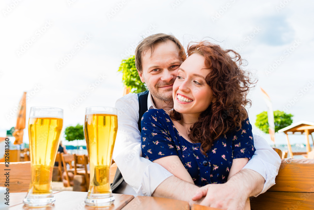 Amorous couple cuddling and drinking in beer garden Amorous couple cuddling and drinking in beer garden