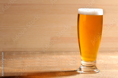 Light beer in a glass glass on a brown wooden background