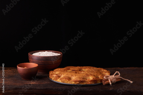 On a dark wooden table american apricot pie, ingredients and tools on black background photo