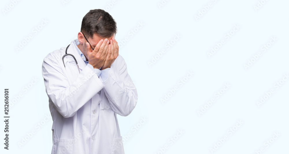 Handsome young doctor man with sad expression covering face with hands while crying. Depression concept. Handsome young doctor man with sad expression covering face with hands while crying. Depression concept.