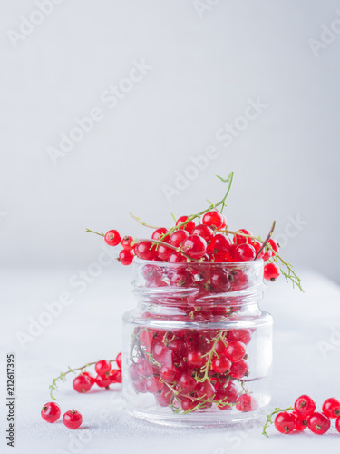 Ripe red currant in a glass jar on a light background. Summer minimalistic concept. photo