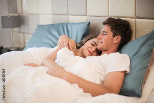 Happy couple in bed in a hotel.