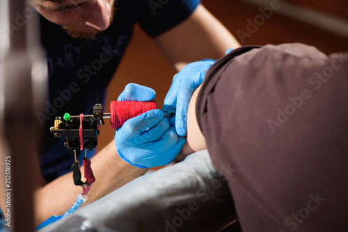 Tattoo artist creating a tattoo on a man's arm.